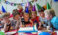 Kinder mit Partyhüten vor einer Geburtstagstorte